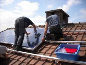 Two men installing a solar panel on a roof