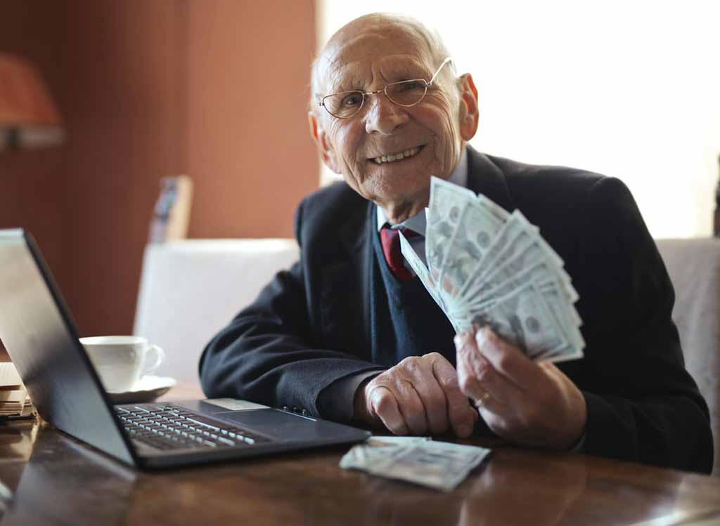 A senior businessman in a suit holding a lot of money.