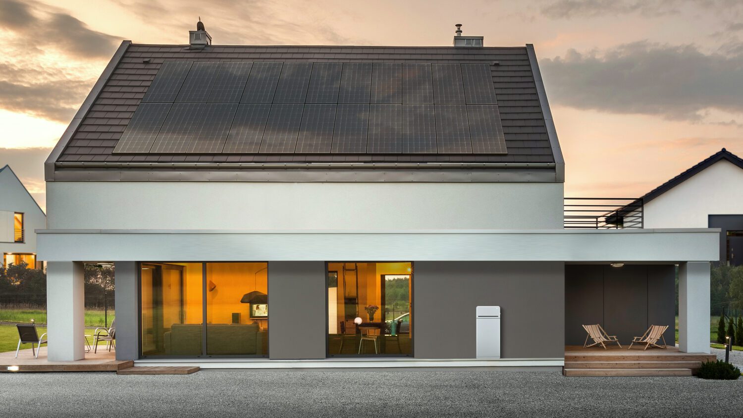 Modern contemporary solar-paneled house at sunset with solar battery sitting against exterior wall