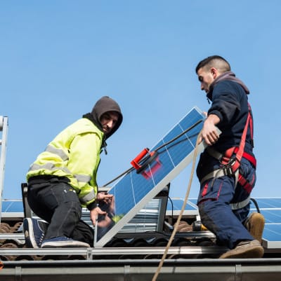 Men lifting a solar panel attached to a harness