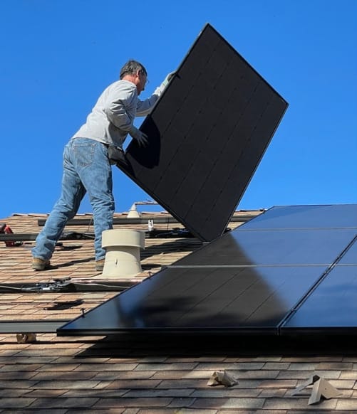 Man placing a panel into position on a rooftop during solar panel installation